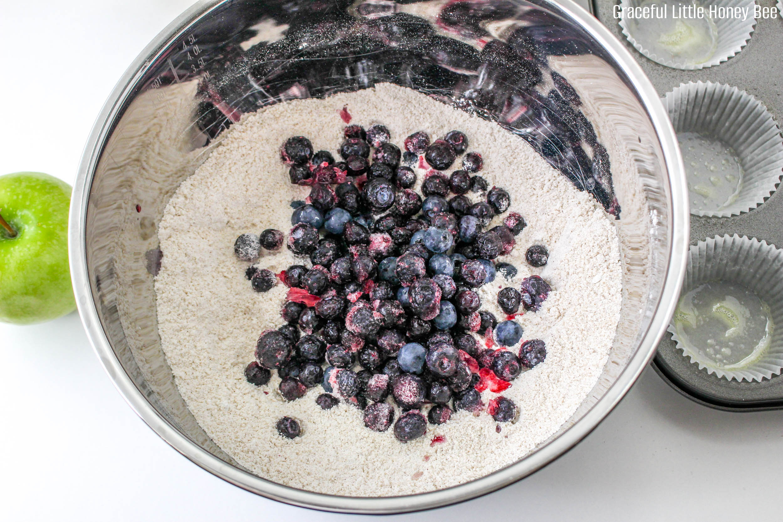 Dry ingredients with blueberries in a metal mixing bowl.