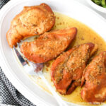 Aerial view of four brown sugar chicken breasts on an oval white platter.