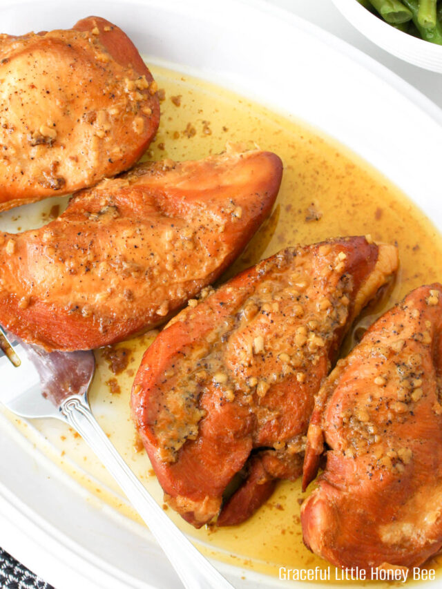 Aerial view of four brown sugar chicken breasts on an oval white platter.