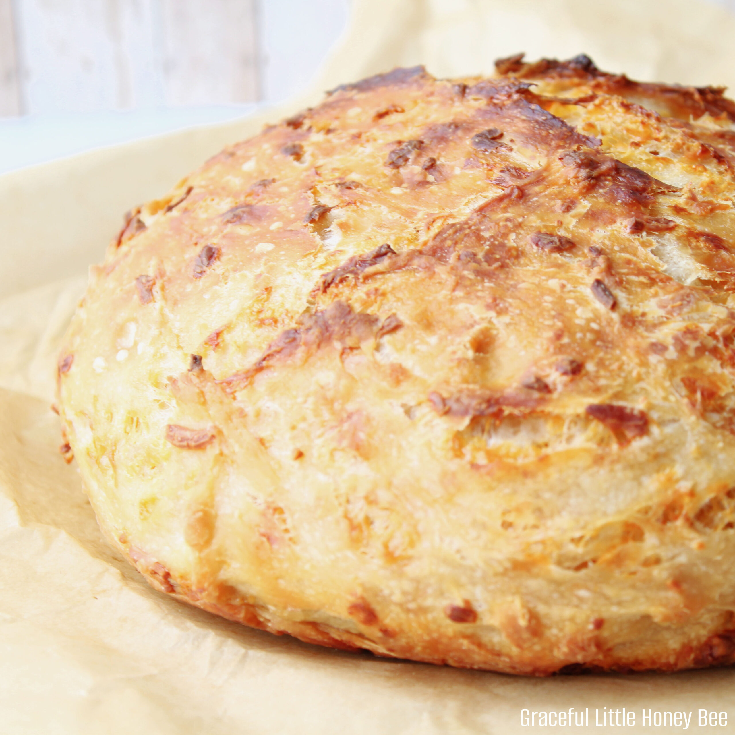 A close up view of the rustic no knead cheddar bread sitting on a cutting board.