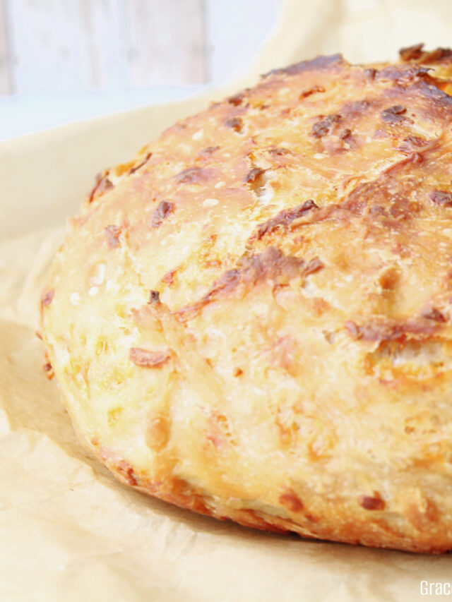 A close up view of the rustic no knead cheddar bread sitting on a cutting board.