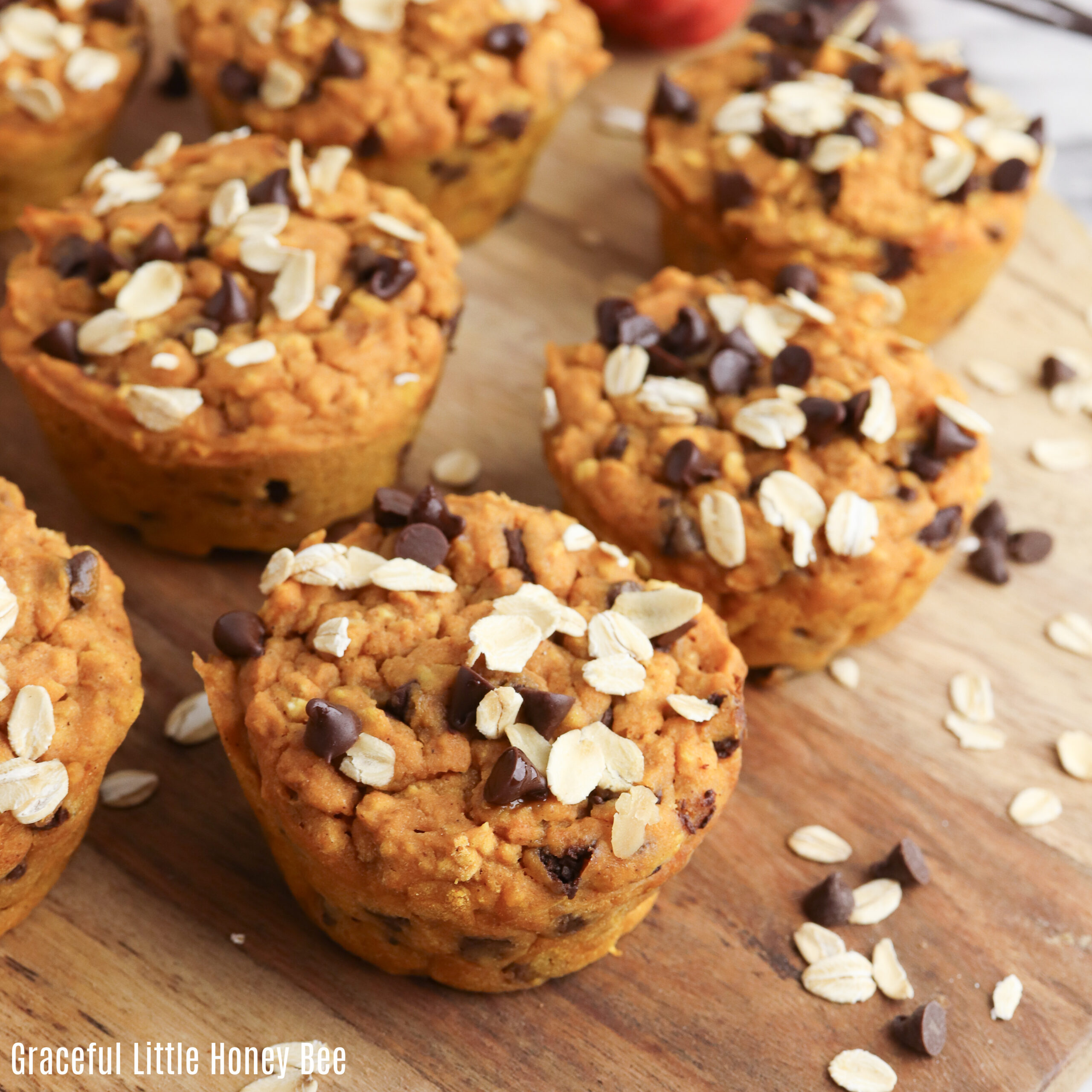 A close up view of pumpkin oat muffins on a wooden cutting board.