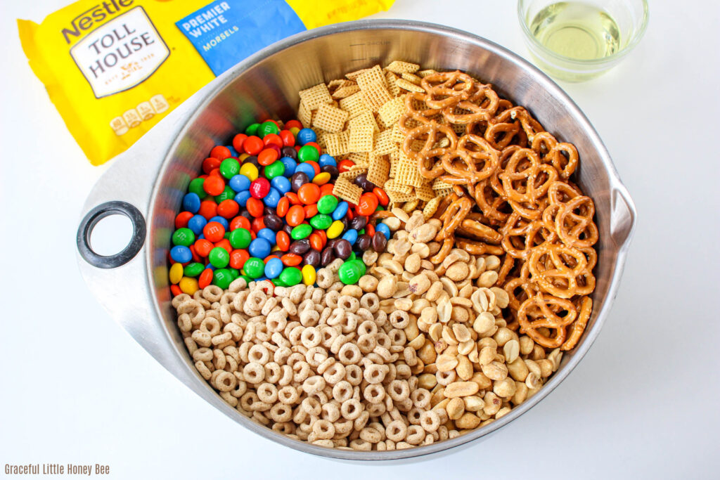 Cereal, peanuts, pretzels and candies in a large mixing bowl.