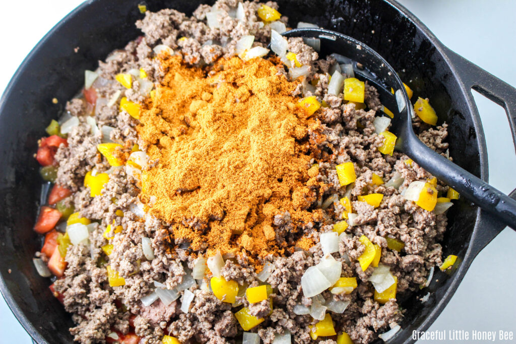 Beef mixture with seasonings on top in skillet.