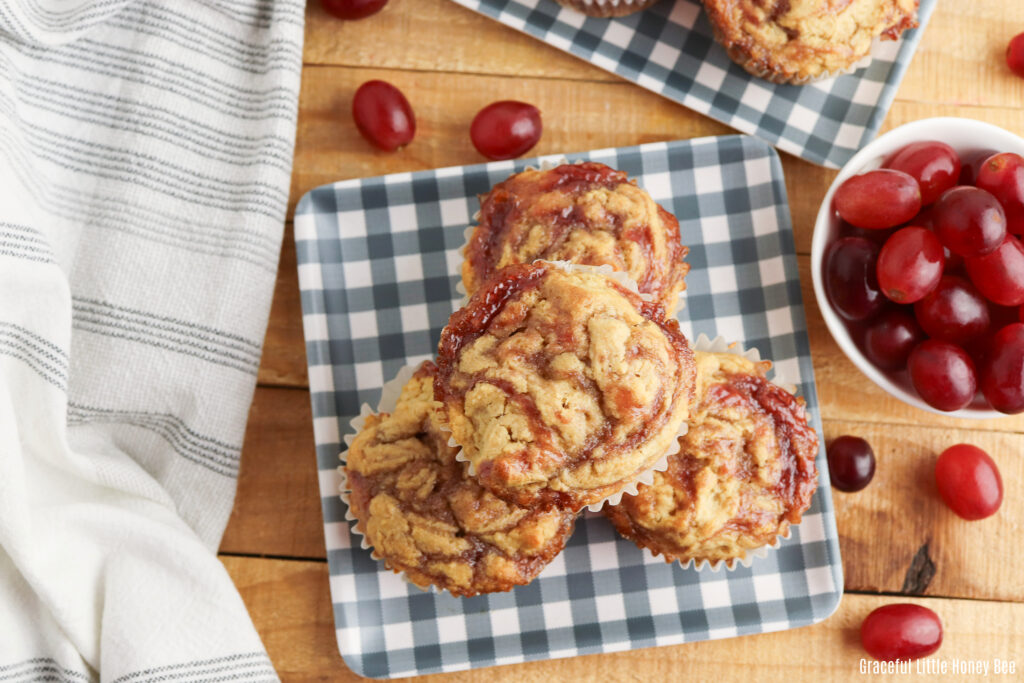 Peanut butter and jelly muffins sitting on a blue and white gingham plate.