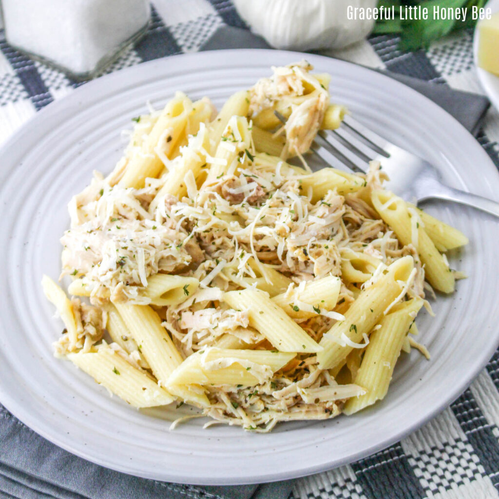 Close up of garlic Parmesan chicken over pasta on a white plate.