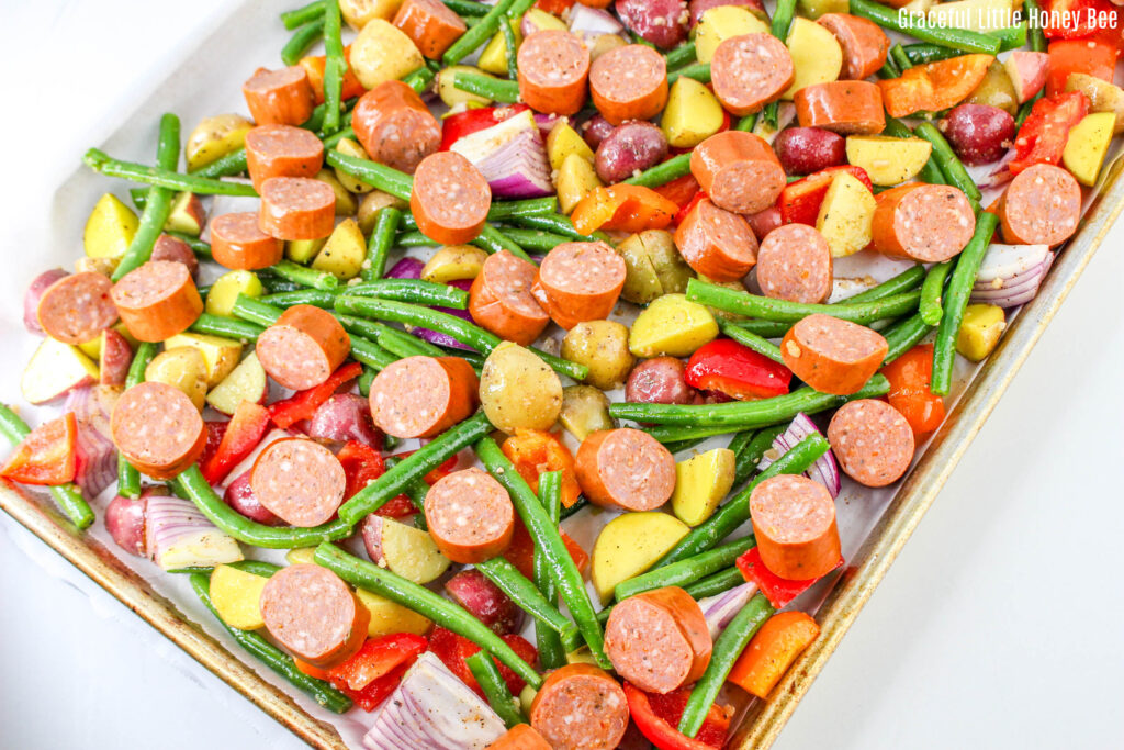 Sausages and vegetables on a sheet pan before going into the oven.