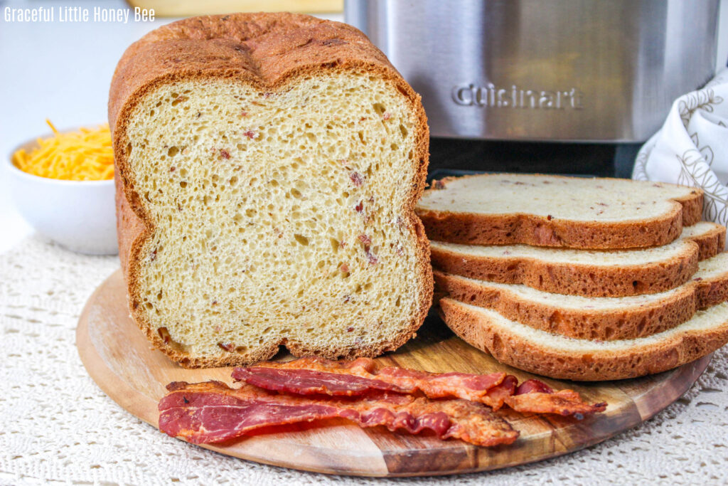 Bacon Cheddar Bread sliced and sitting on a cutting board next to slices of bacon.