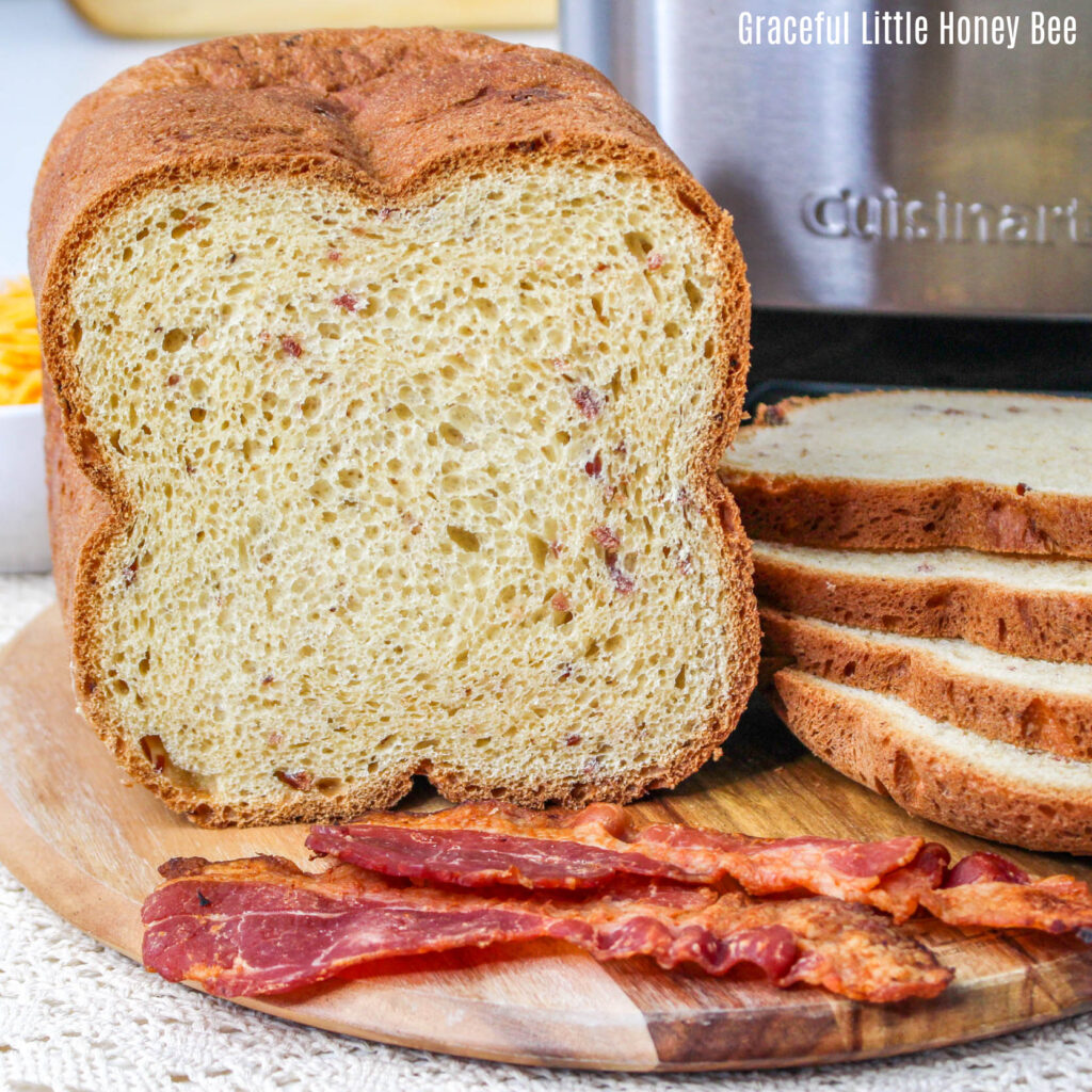 Bacon Cheddar Bread sliced and sitting on a cutting board next to slices of bacon.