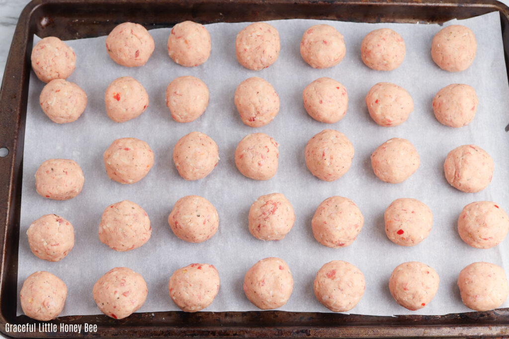 Sausage balls on a baking sheet before going into the oven.