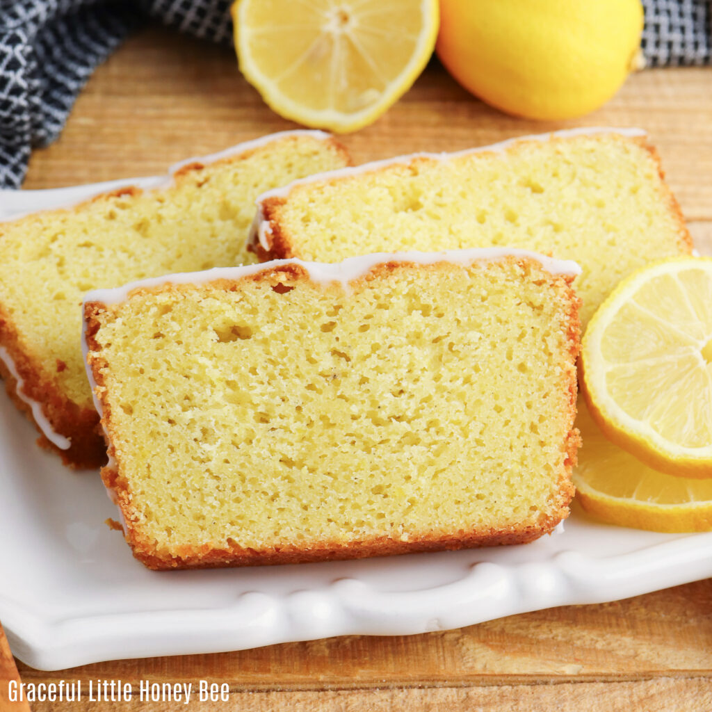 Thick slices of iced lemon loaf sitting on a white platter.