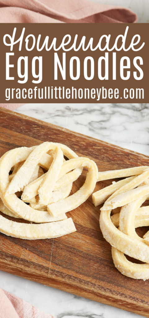 Egg noodles sitting on a wooden cutting board.