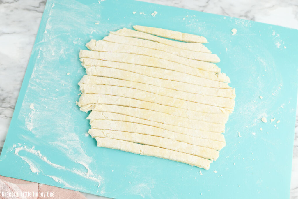 Pasta cut into strips on a cutting mat.