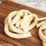 Egg noodles sitting on a wooden cutting board.