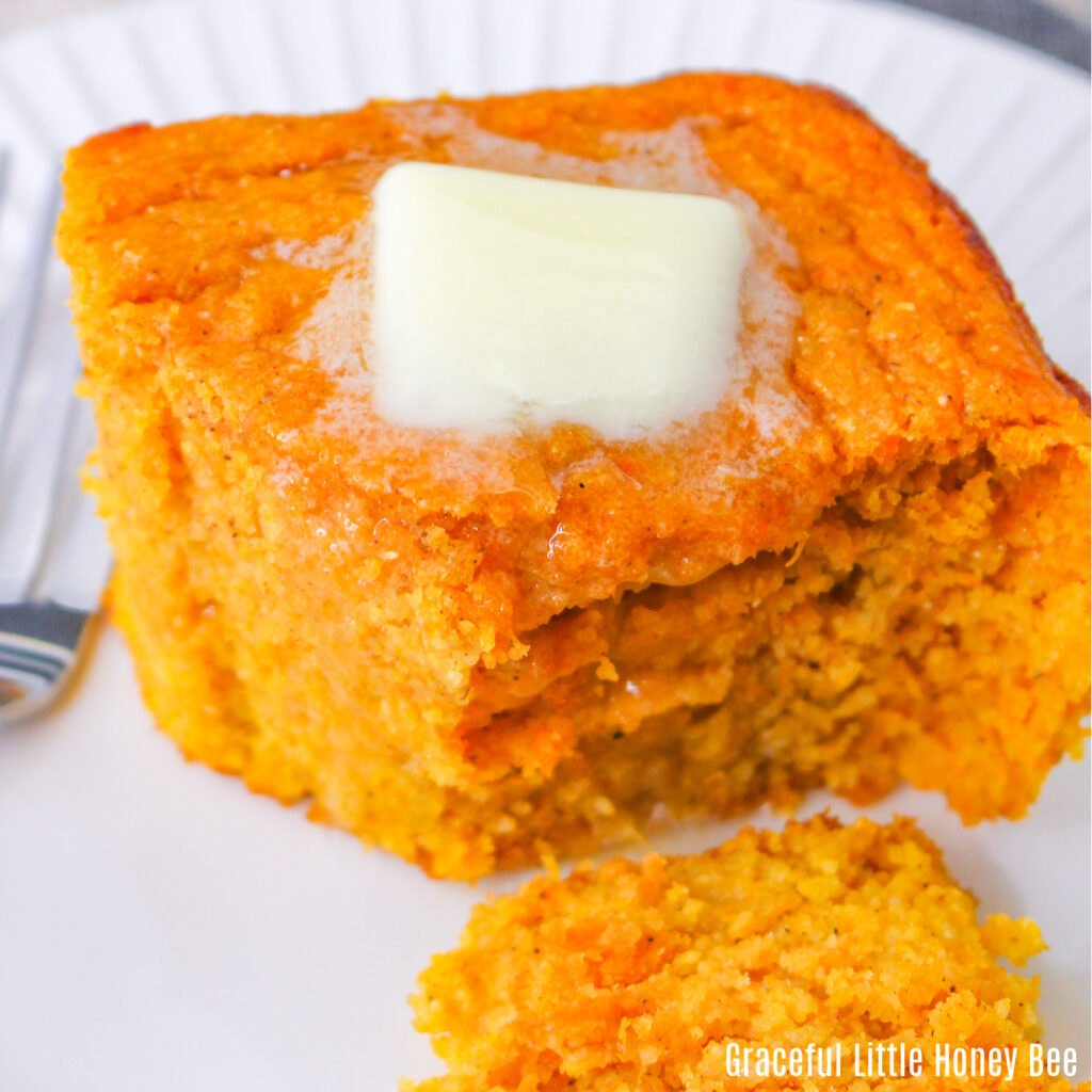 A close up view of a slice of spoonbread with a pat of butter on top.