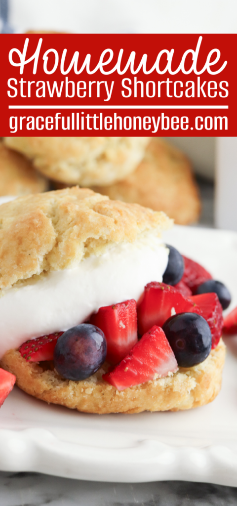 A close up view of a homemade shortcake cut in half and topped with whipped cream and fresh berries.