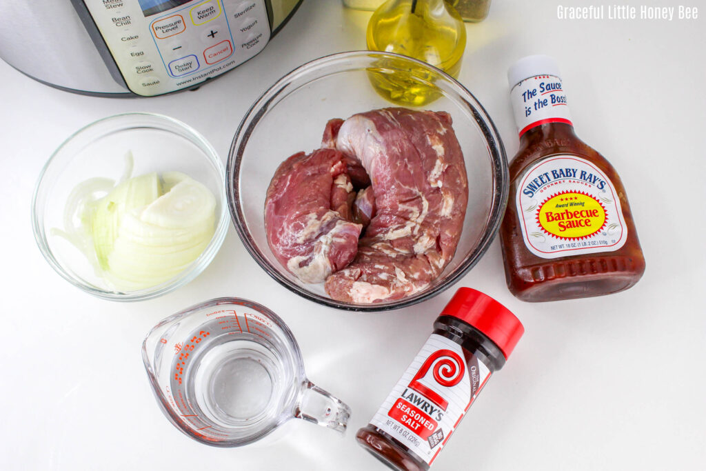 Pork tenderloin, season salt, bbq sauce, olive oil, water and sliced onions sitting on a countertop.