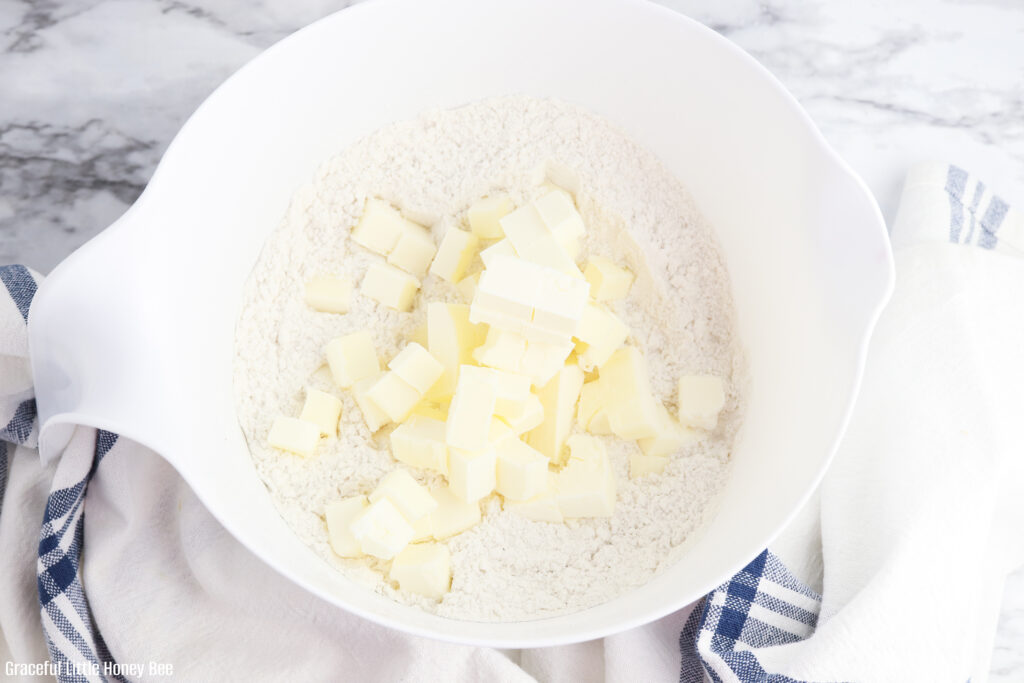 Dry ingredients with cut up butter on top in a mixing bowl.
