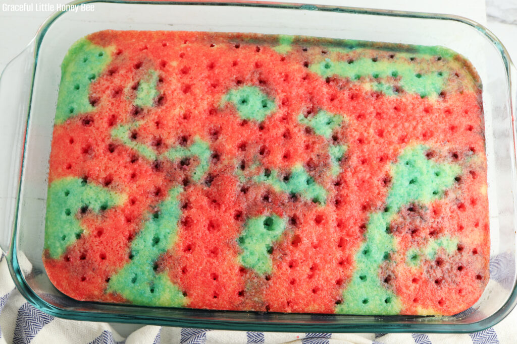 White cake with holes poked on top and red and blue jello soaked into the it.