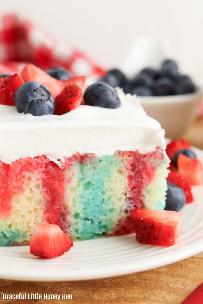Square serving of jello poke cake with fresh berries on top.
