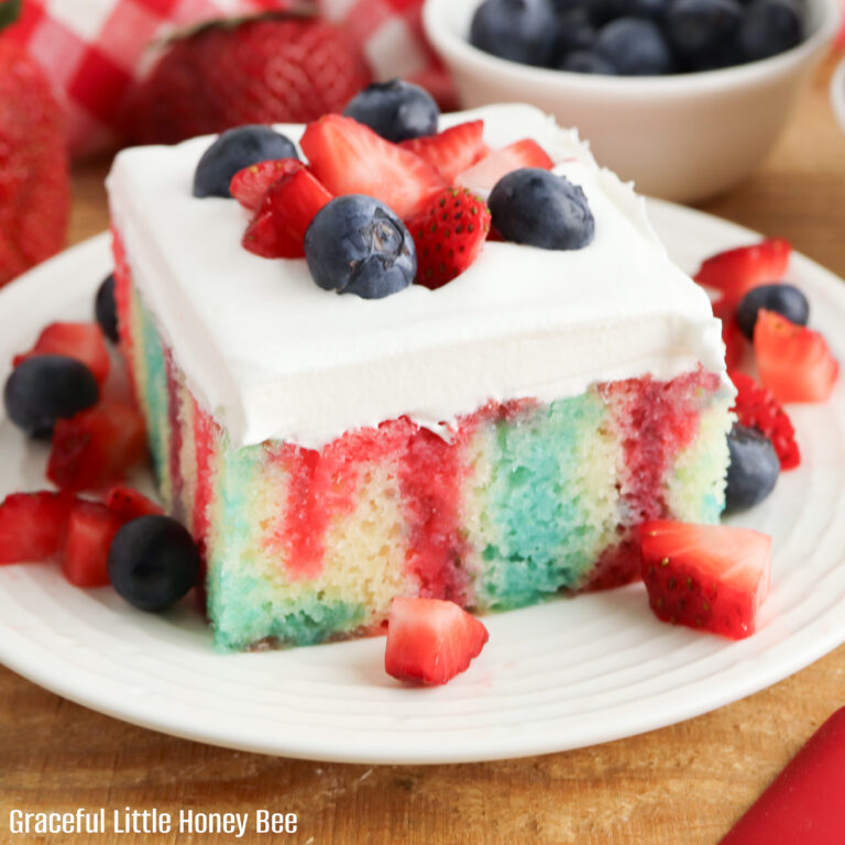 Square serving of jello poke cake with fresh berries on top.