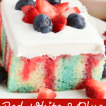 Square serving of jello poke cake with fresh berries on top.