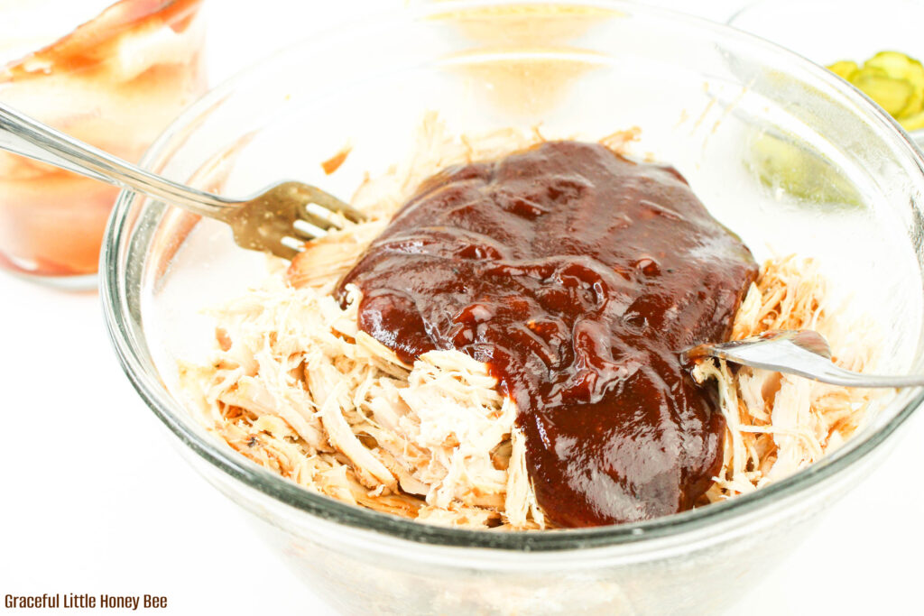 Shredded chicken with bbq sauce on top in a clear bowl.