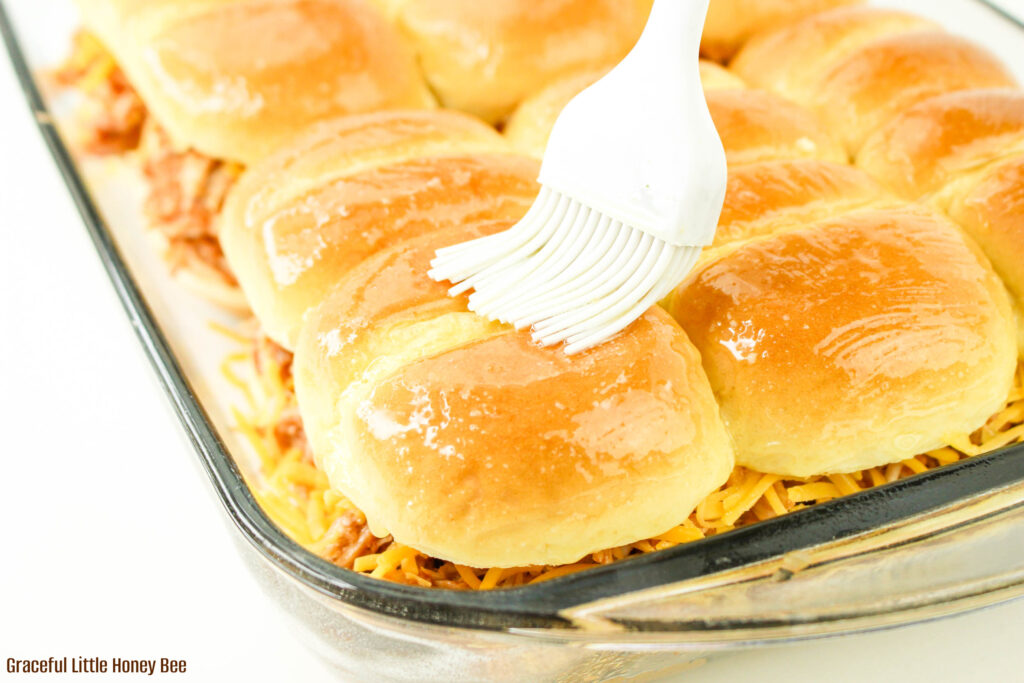 Slider buns being basted with melted butter.