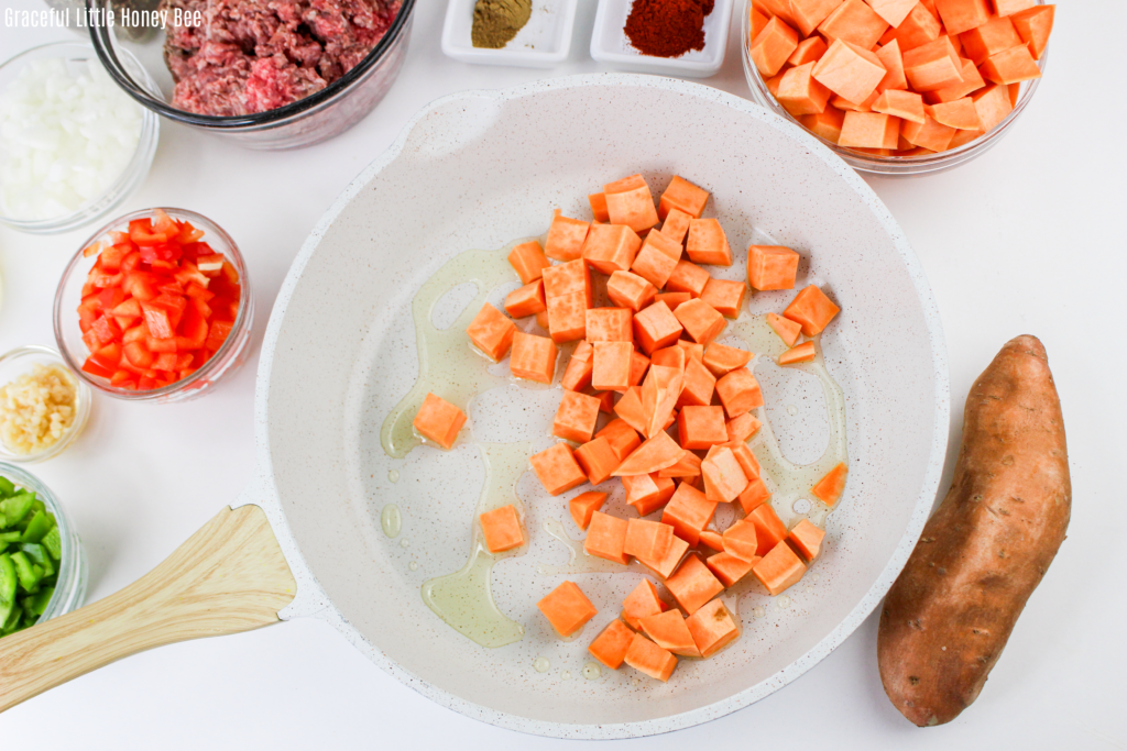 Diced sweet potatoes in a white skillet.