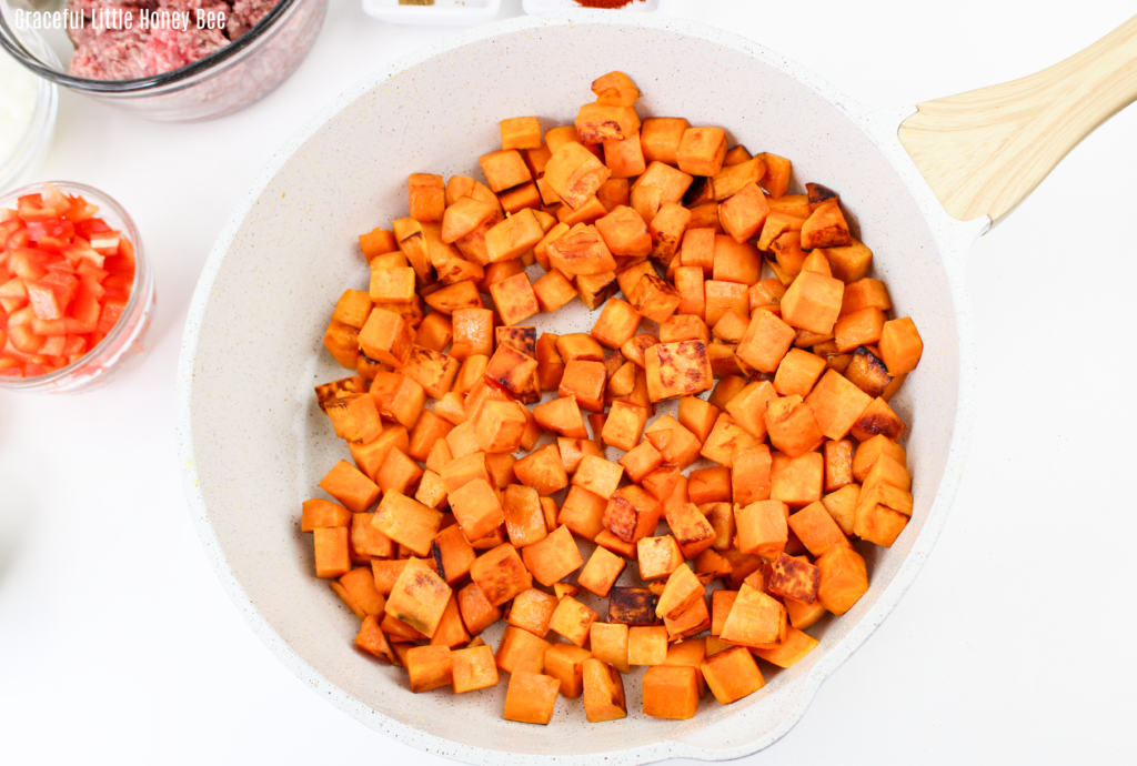 Diced sweet potatoes in a white skillet.