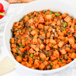Close up view of beef & sweet potato hash in a white skillet.