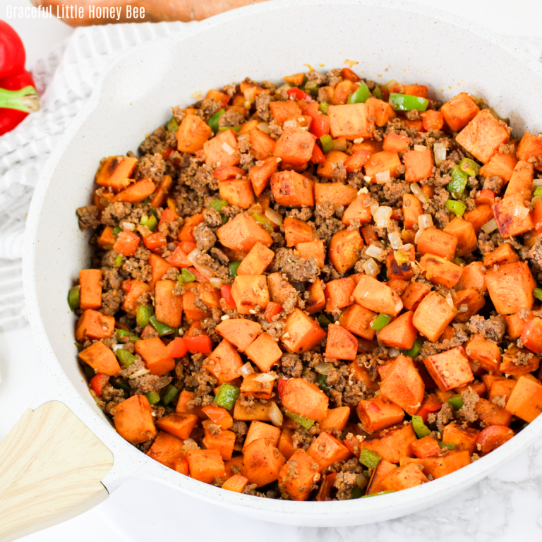 Close up view of beef & sweet potato hash in a white skillet.