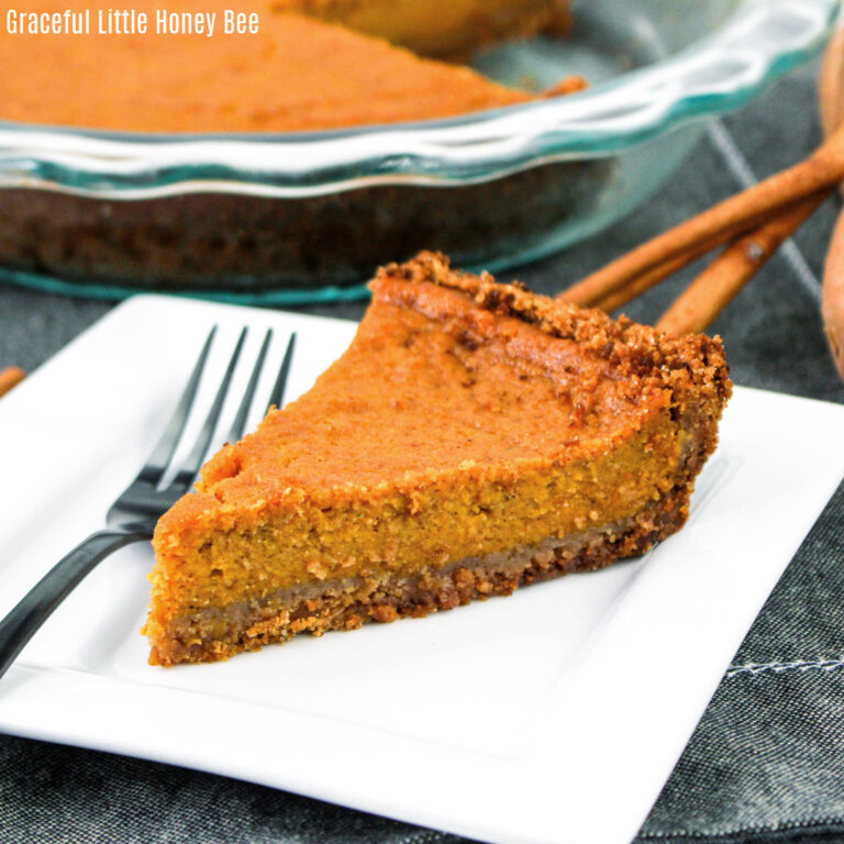 A slice of sweet potato pie on a square white plate with a fork sitting next to it.