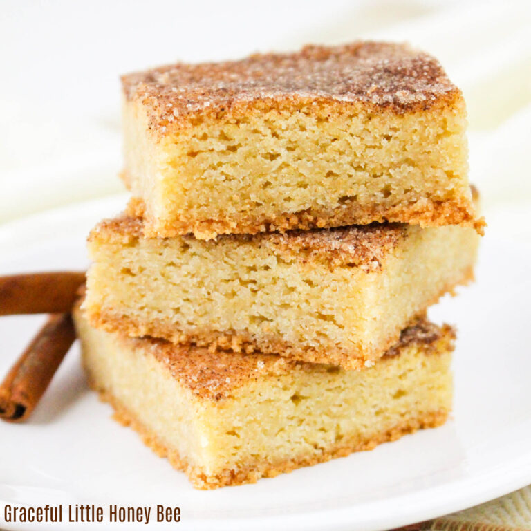 Stack of three snickerdoodle bars on a white plate with a cinnamon stick sitting next to it.