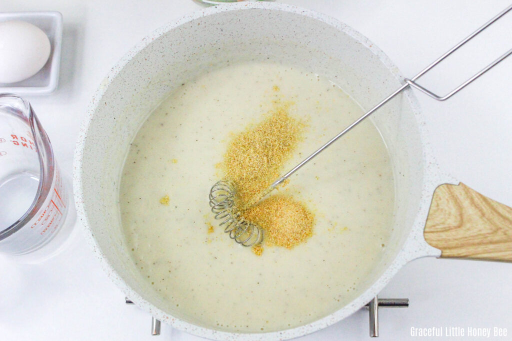 Cream sauce with seasonings on top in saucepan.
