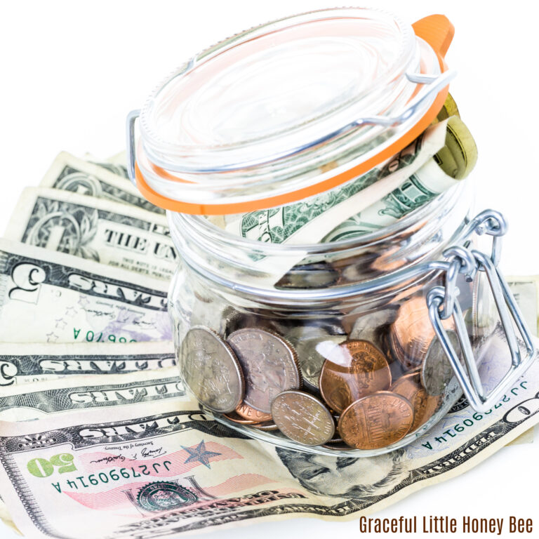 A glass jar filled with change and sitting on top of bills.