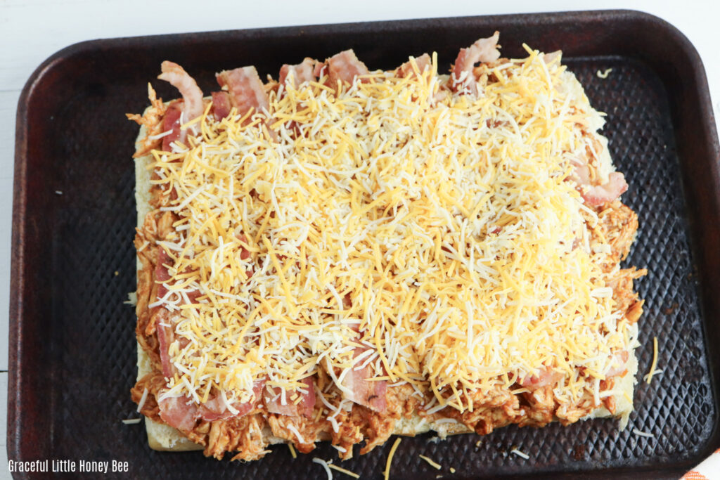 Slider bun topped with BBQ chicken, bacon and shredded cheese.