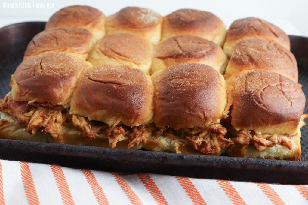 Golden brown sliders sitting on a black baking pan.