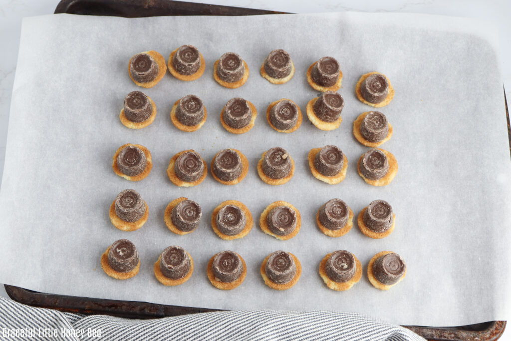 Nilla Wafers with Rollo candy on top on a baking sheet.