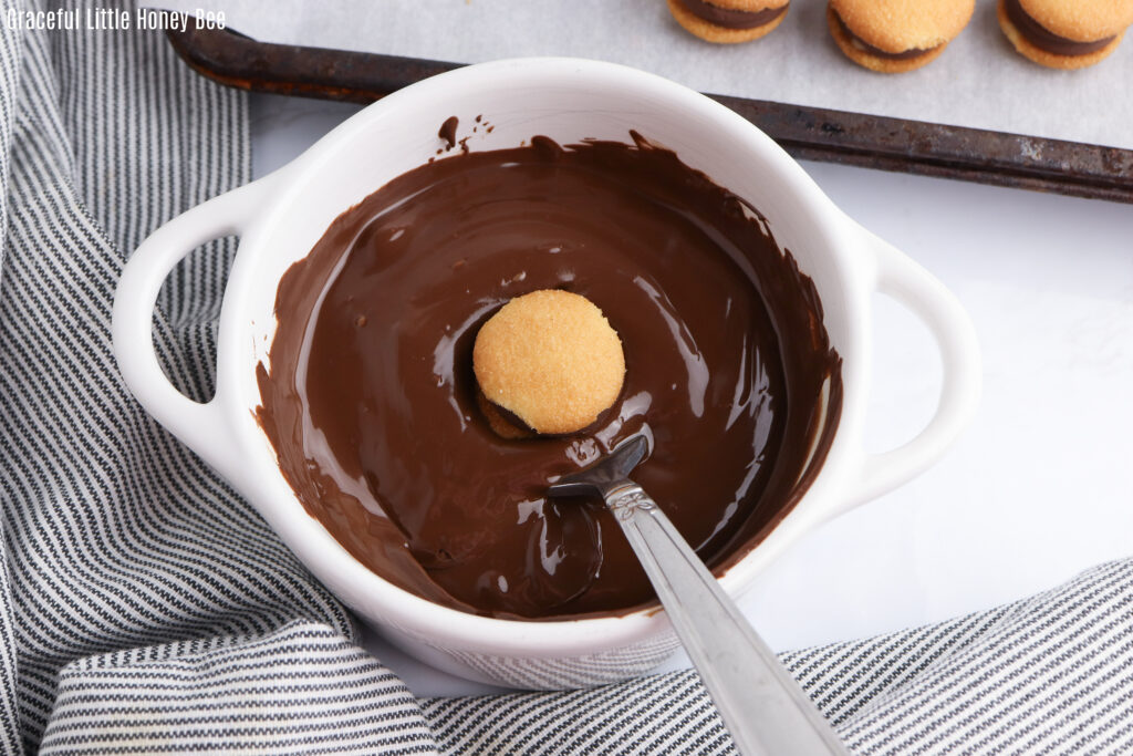 Melted chocolate in a bowl with a cookie dipped into it.