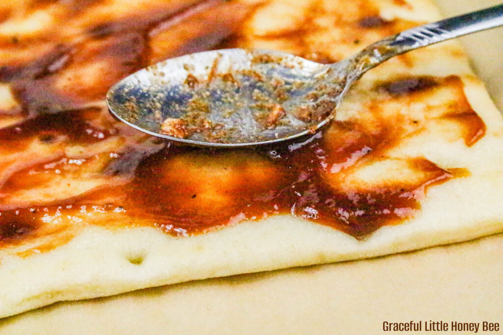 BBQ being bread atop flatbread with a spoon.