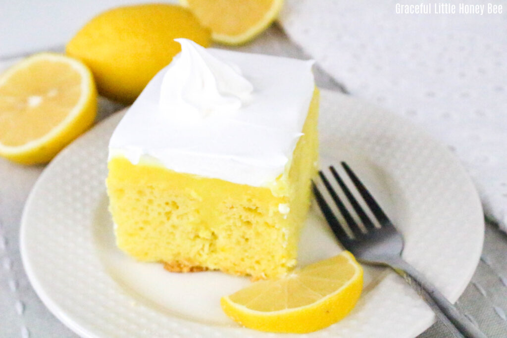 A square of lemon pudding poke cake on a round white plate.