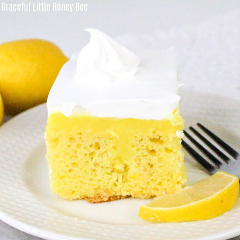 A square of lemon pudding poke cake on a round white plate.
