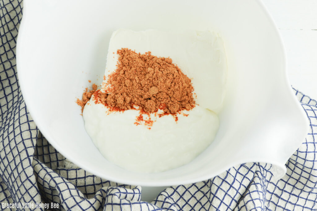 Aerial view of sour cream and taco seasoning in a mixing bowl.