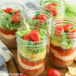 Close up view of seven layer dip in a half pint jar.