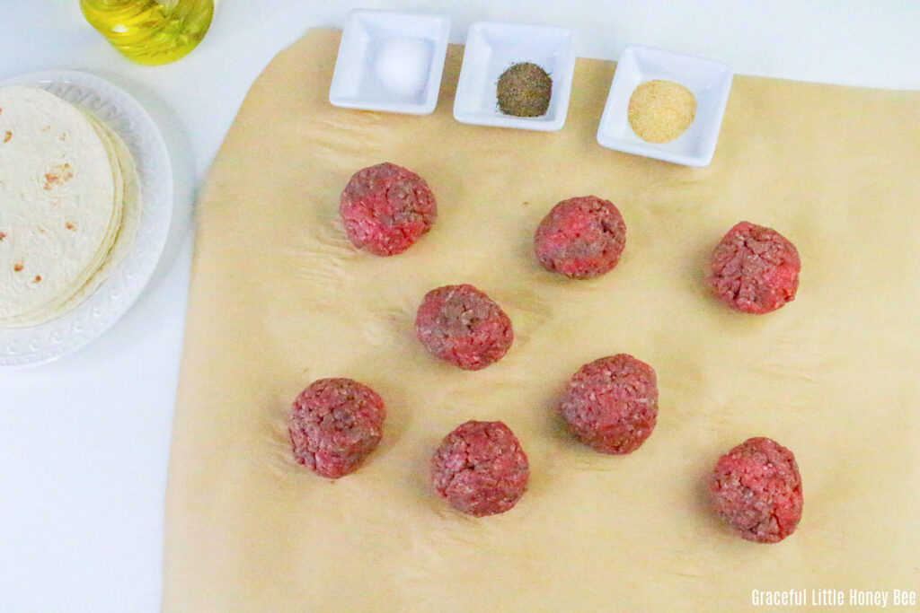 Raw meatballs sitting on parchment paper.