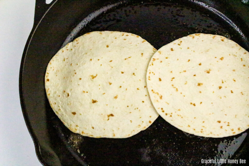 Smashed beef topped with tortillas in a skillet.