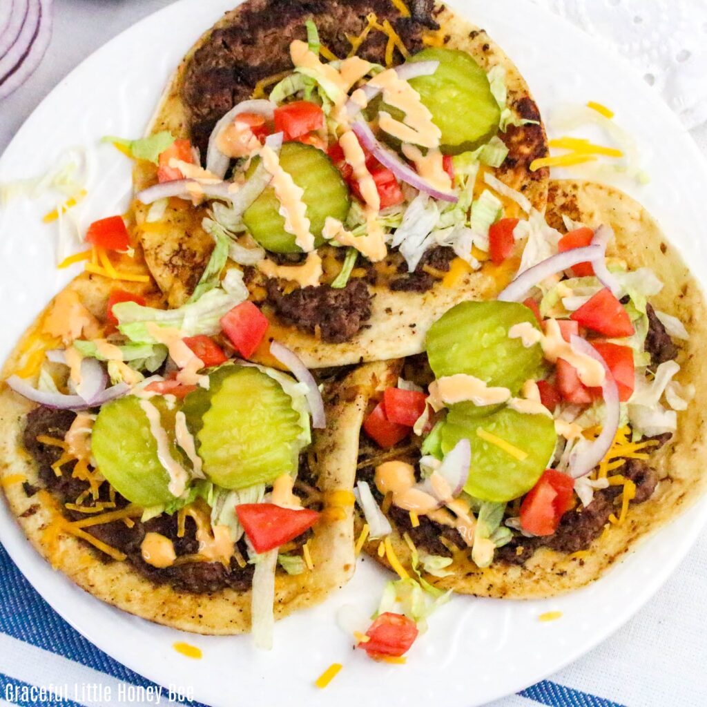 Aerial view of three smash burger tacos on a white plate.