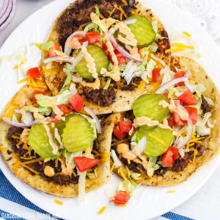Aerial view of three smash burger tacos on a white plate.