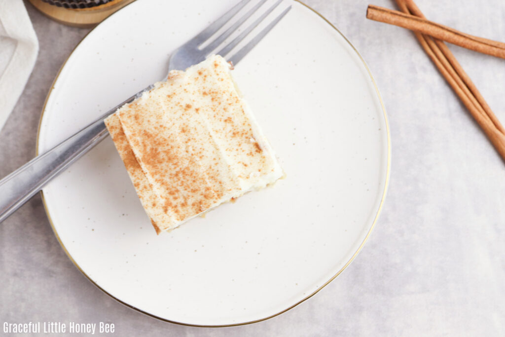 Top view of a cinnamon roll poke cake on a white plate.